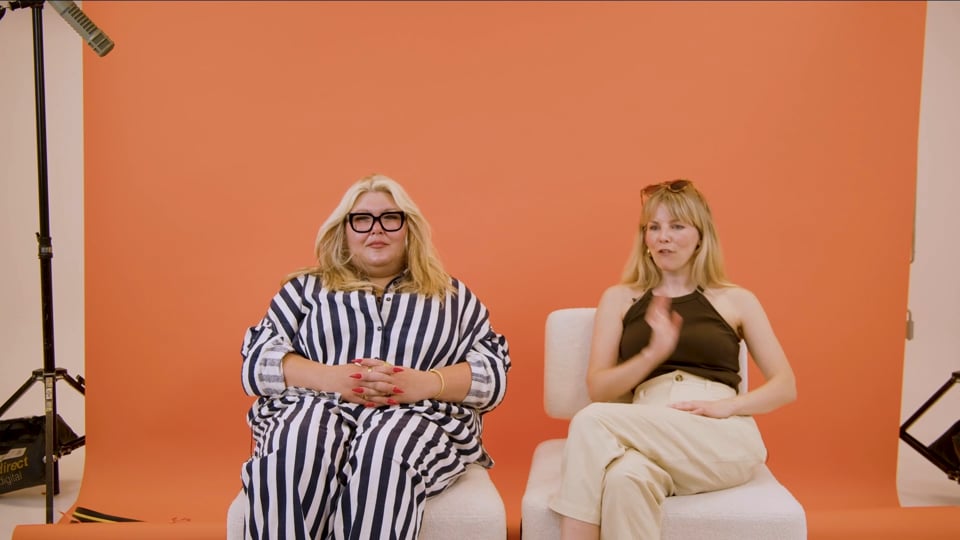 The two Ghost Huns hosts seated against an orange backdrop in the official creator interview.