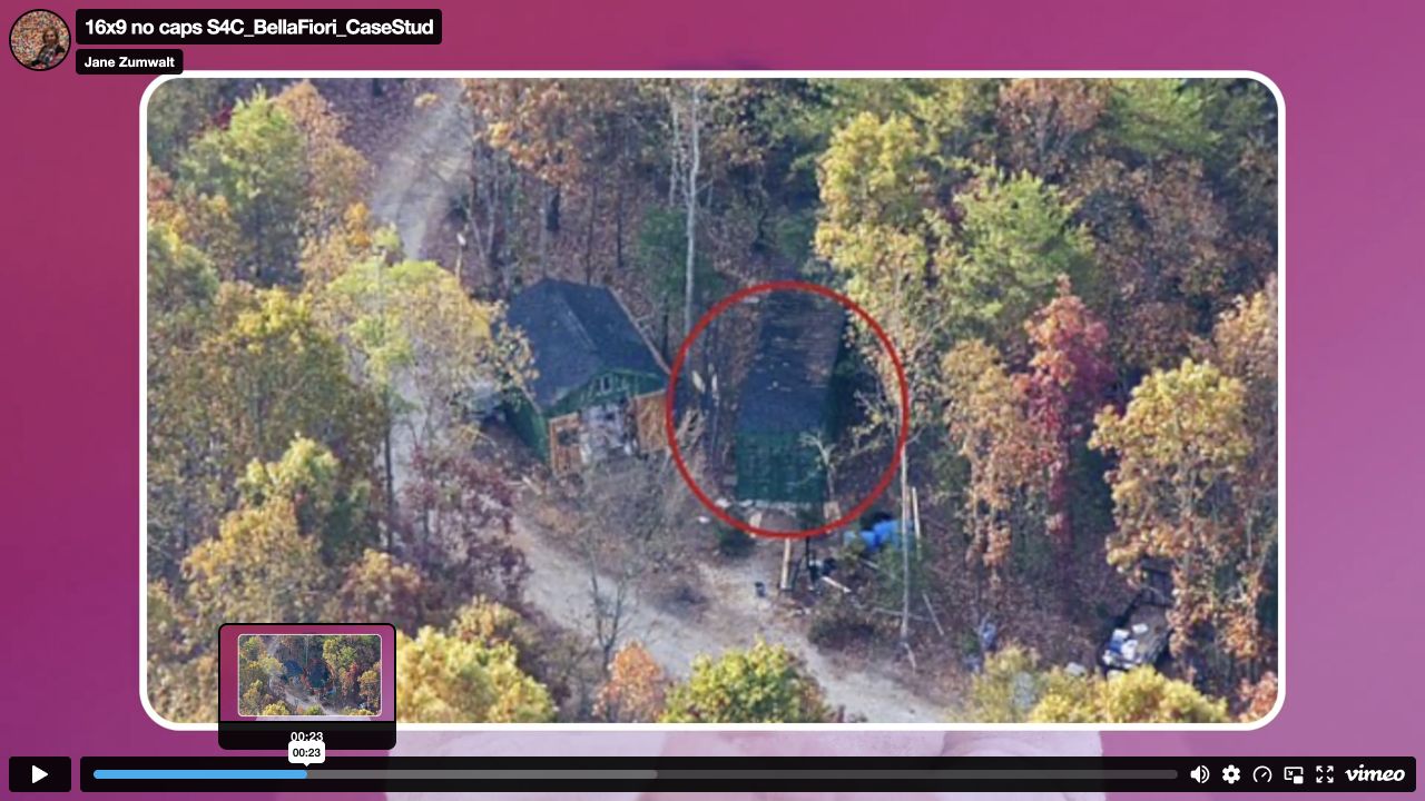 Official interview paused at 00:23, showing an overhead photograph of buildings among trees and a red circle around one structure.