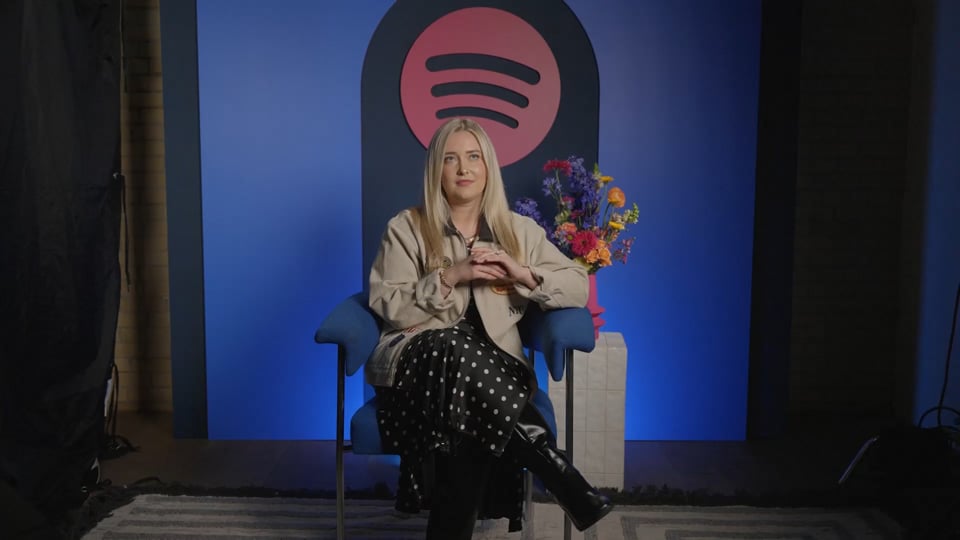 Morgan Absher seated in a blue chair during the interview embedded in Spotify’s Two Hot Takes case study.